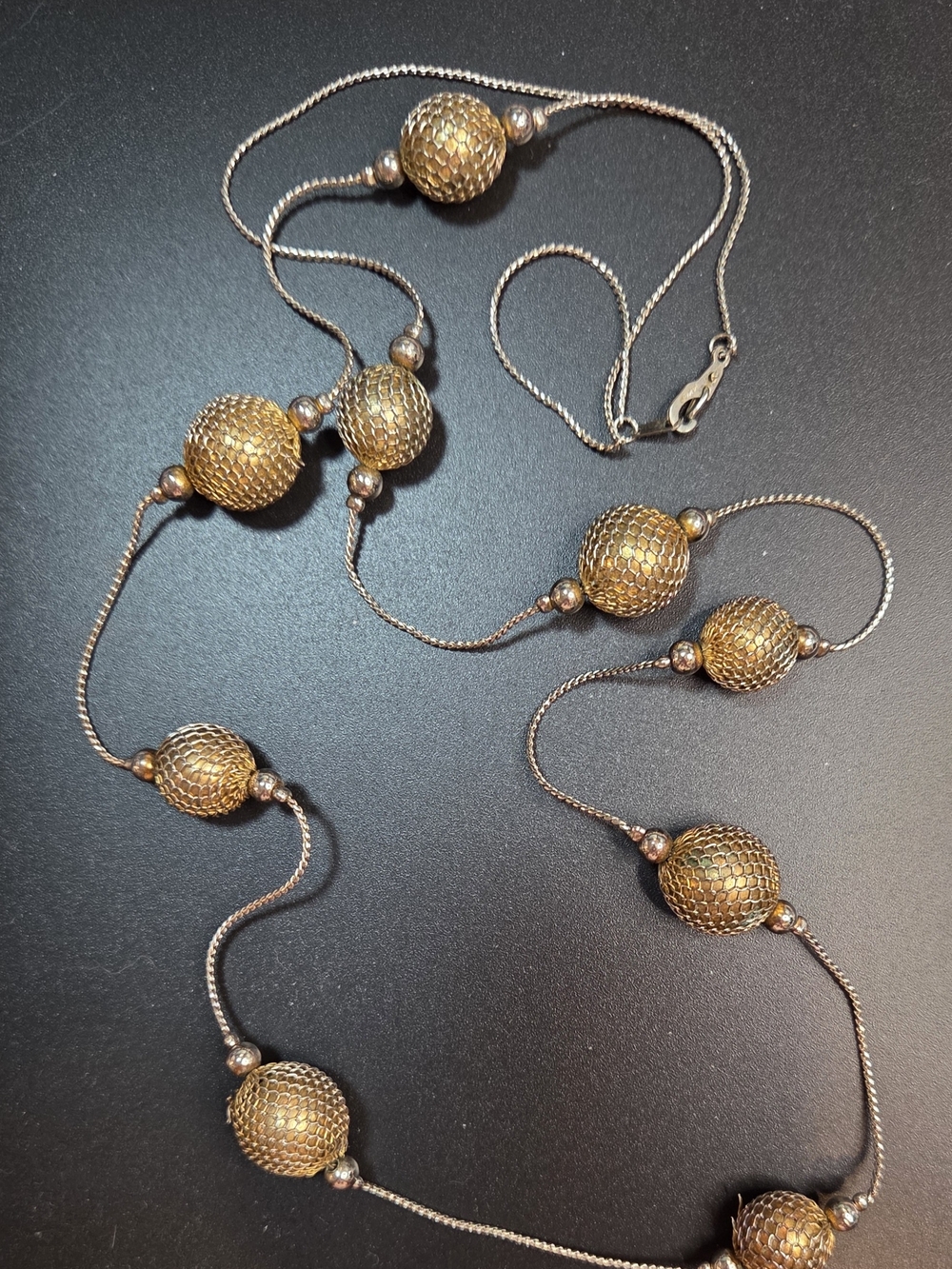 Vintage long station necklace characterized by multiple mesh-covered beads.